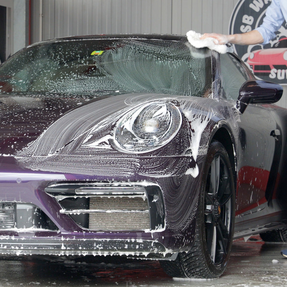 Autoshampoo-Schaum am Scheinwerfer und an der Front eines violetten Porsche 911