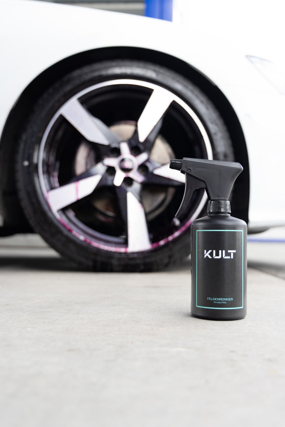 KULT Felgenreiniger 500 ml mit Premium Sprühkopf vor der Felge eines weißen Audi A6