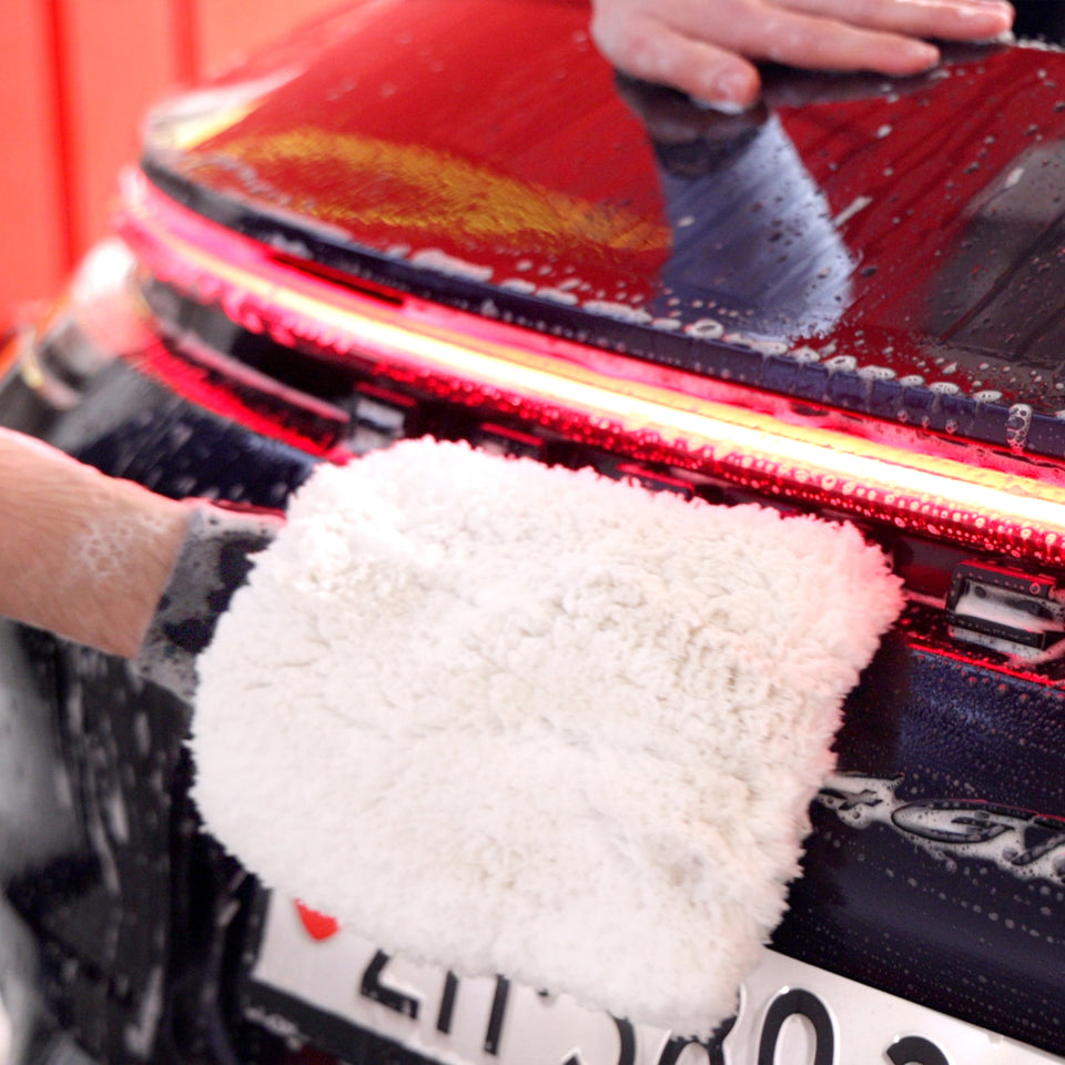 Weißer Waschhandschuh am Heck eines Porsche 911 unterhalb der roten Lichtleiste