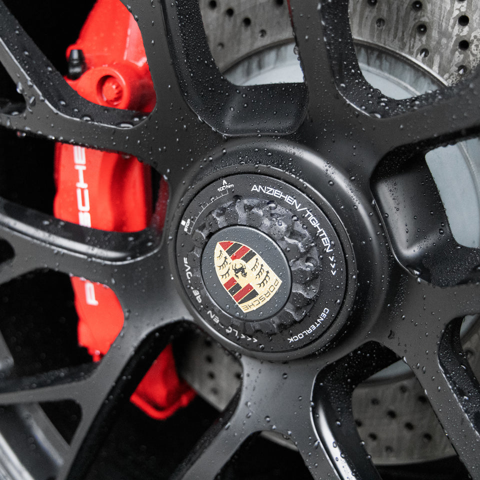 Nahaufnahme einer sauberen schwarzen Porsche-Felge mit rotem Bremssattel