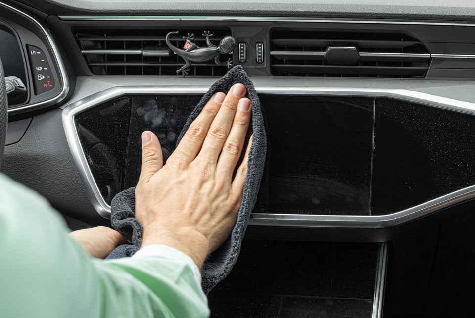 Das Display im Cockpit eines Audi A6 wird mit einem Mikrofasertuch und Innenraumreiniger gereinigt