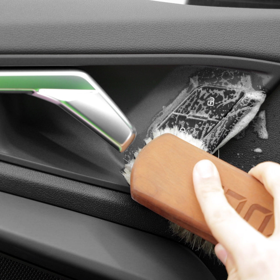 Die Fensterheber-Schalter in der Türverkleidung eines Audi RS3 werden mit Innenraumreiniger und Rosshaarbürste gereinigt