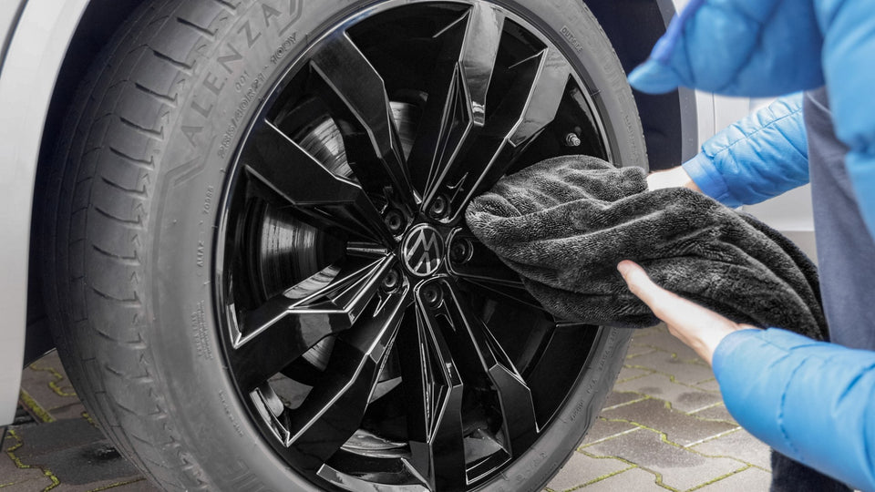 Schwarze Felge eines VW Touareg wird nach der Wäsche mit einem Trockentuch getrocknet