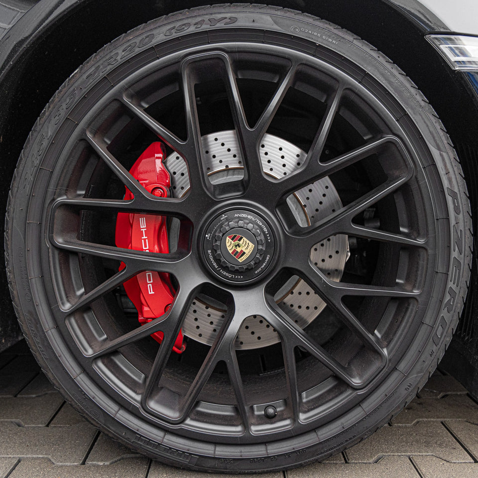 Saubere schwarze Porsche-Felge mit roten Bremssätteln nach der Felgenreinigung