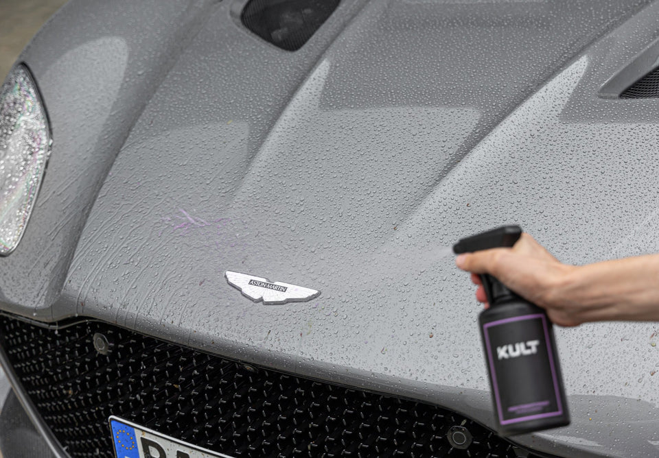 KULT Insektenentferner 500 ml mit Sprühkopf vor der Fronthaube eines Aston Martin