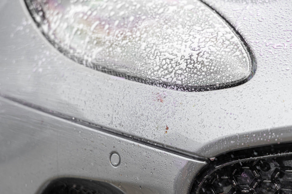 Insektenentferner wirkt als Gel-Schaum auf dem Scheinwerfer eines Aston Martin DBS ein