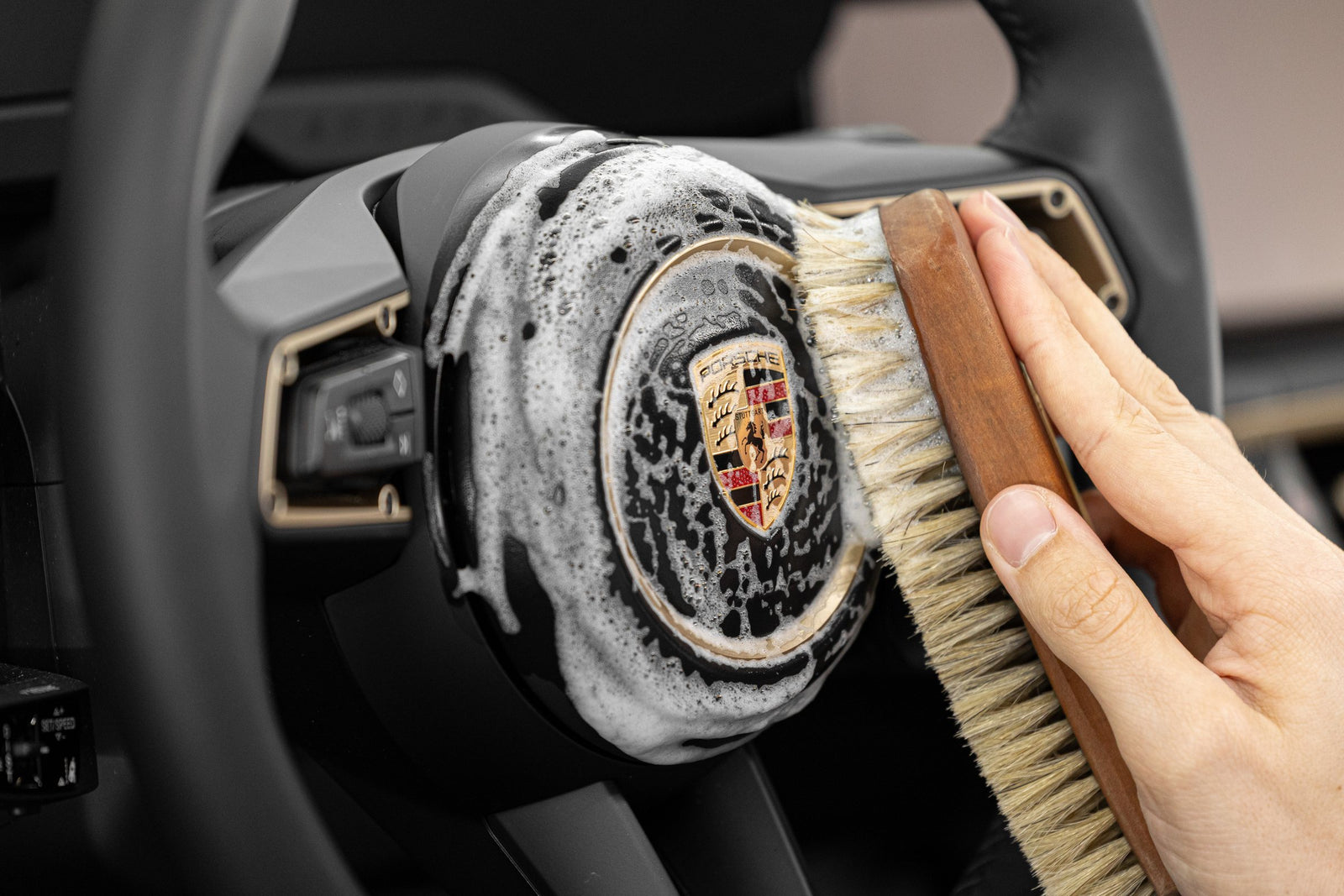 Lederpflege im Porsche Taycan: Das Lenkrad wird mit Schaum des KULT Lederreinigers und einer Rosshaarbürste gereinigt