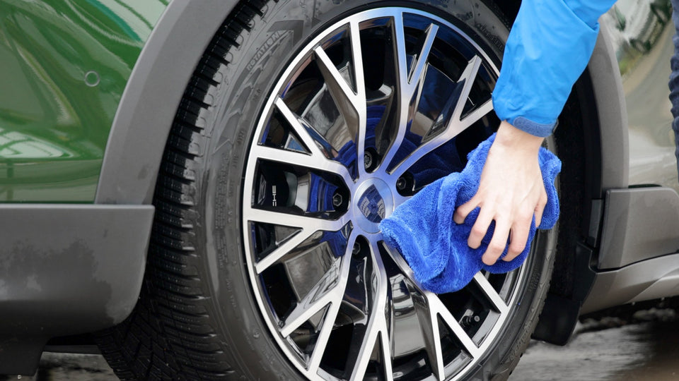 Felge eines dunkelgrünen Porsche Taycan wird nach der Wäsche mit einem blauen KULT Trockentuch nachgetrocknet