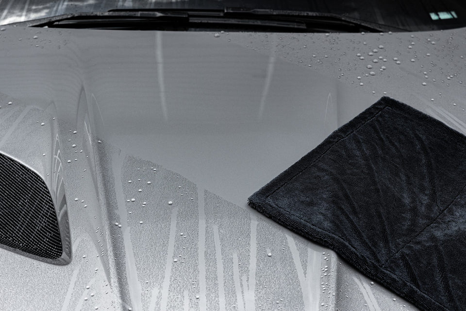 Schwarzes Trockentuch auf der nassen Motorhaube eines silbergrauen Sportwagens
